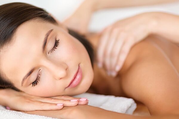 health, beauty, people, body care and relaxation concept - beautiful woman with closed eyes in spa salon getting massage